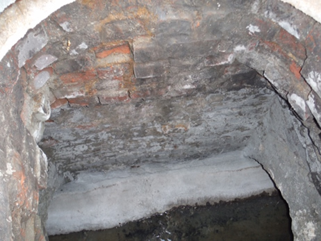A deteriorated, irregular brick manhole